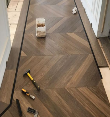 Dark chevron-patterned herringbone flooring with installation tools.