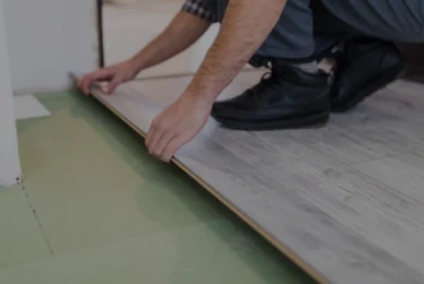Azad Carpets and Furniture fitter installing vinyl flooring over tiles.