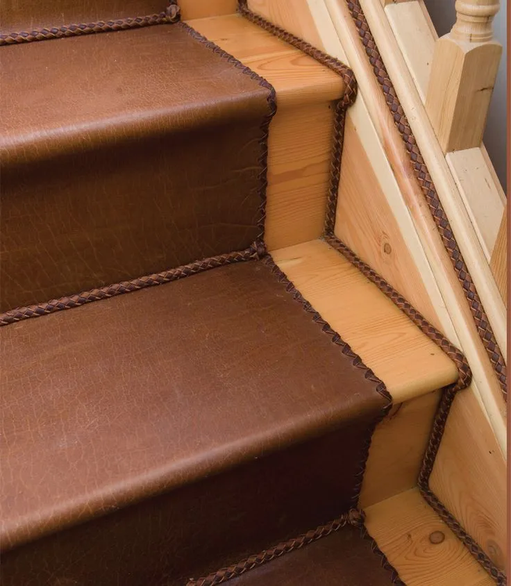  Close-up of a wooden stairway featuring rich brown leather accents, showcasing a stylish alternative to carpeted stairs.